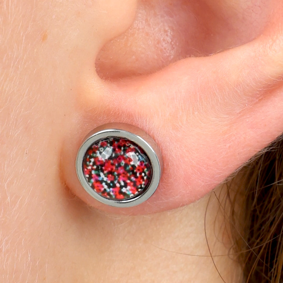 Close-up of an earring with a colorful design on a person's ear.