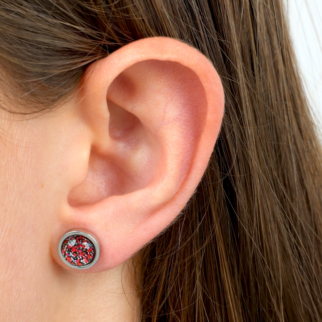 Close-up of an ear wearing a stud earring with a colorful gemstone.