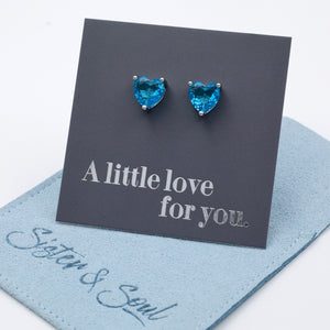 Heart-shaped blue gemstone earrings on a 'A little love for you' card with 'Sister & Soul' branding.
