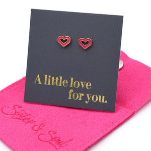 Heart-shaped earrings on a card with 'A little love for you' text, placed on pink fabric with 'Sister & Soul' branding.