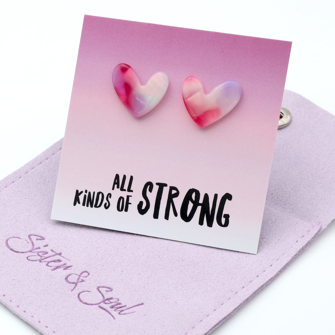 Heart-shaped earrings on a card with 'all kinds of strong' text with a mauve pouch