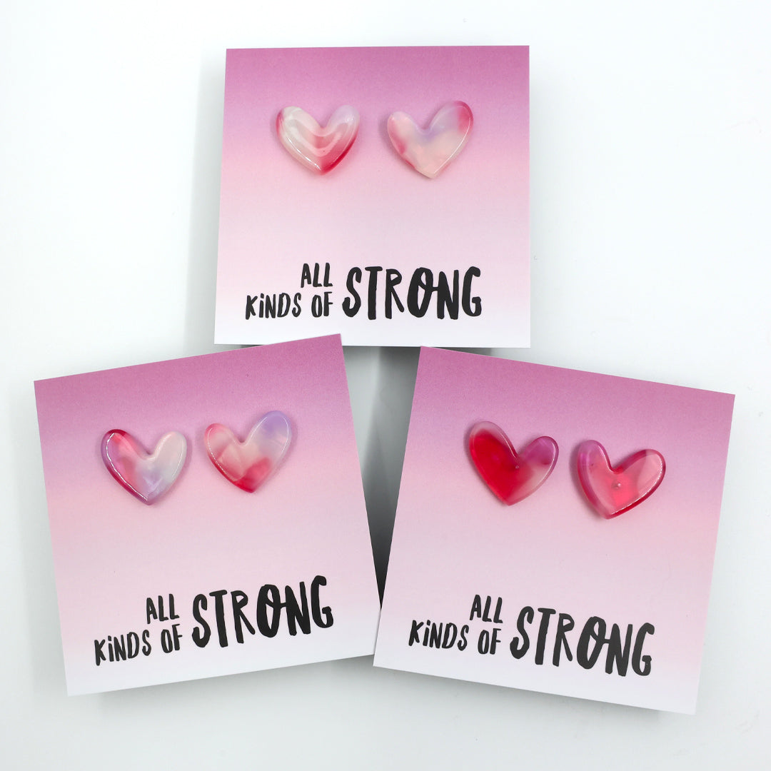 Heart-shaped earrings on a card with 'all kinds of strong' text