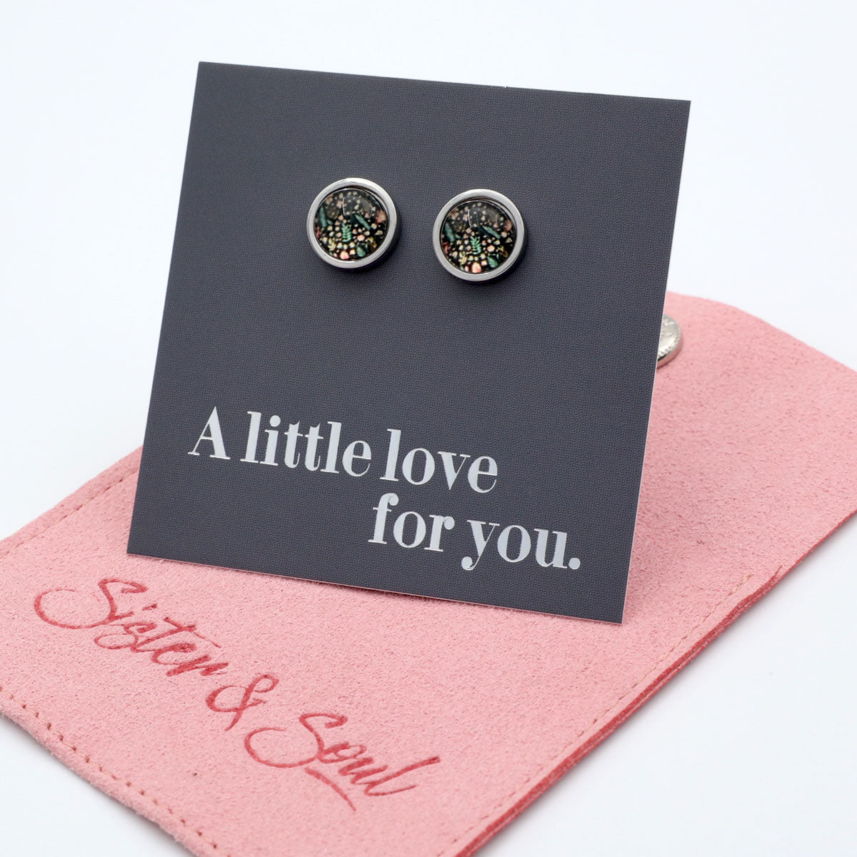Pair of earrings on a card with 'A little love for you' text, placed on a pink felt bag with 'Sister & Soul' branding.