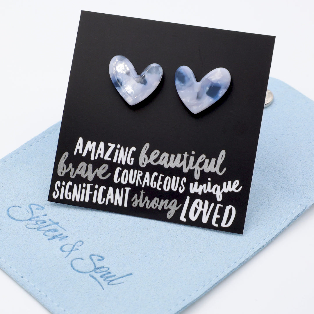 A square black art print or card featuring two marbled heart shapes above stylized white text reading 'AMAZING beautiful brave COURAGEOUS unique SIGNIFICANT strong LOVED'.