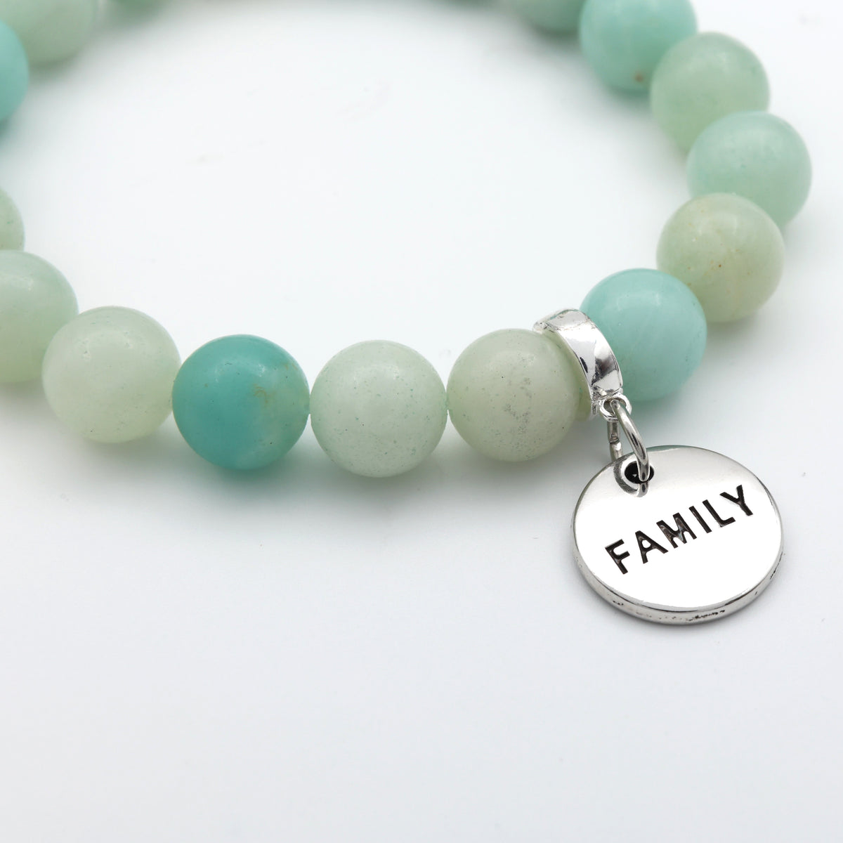 Bracelet with green beads and a silver 'FAMILY' charm on a light background