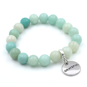 Turquoise and white beaded bracelet with a 'GRATEFUL' charm on a white background