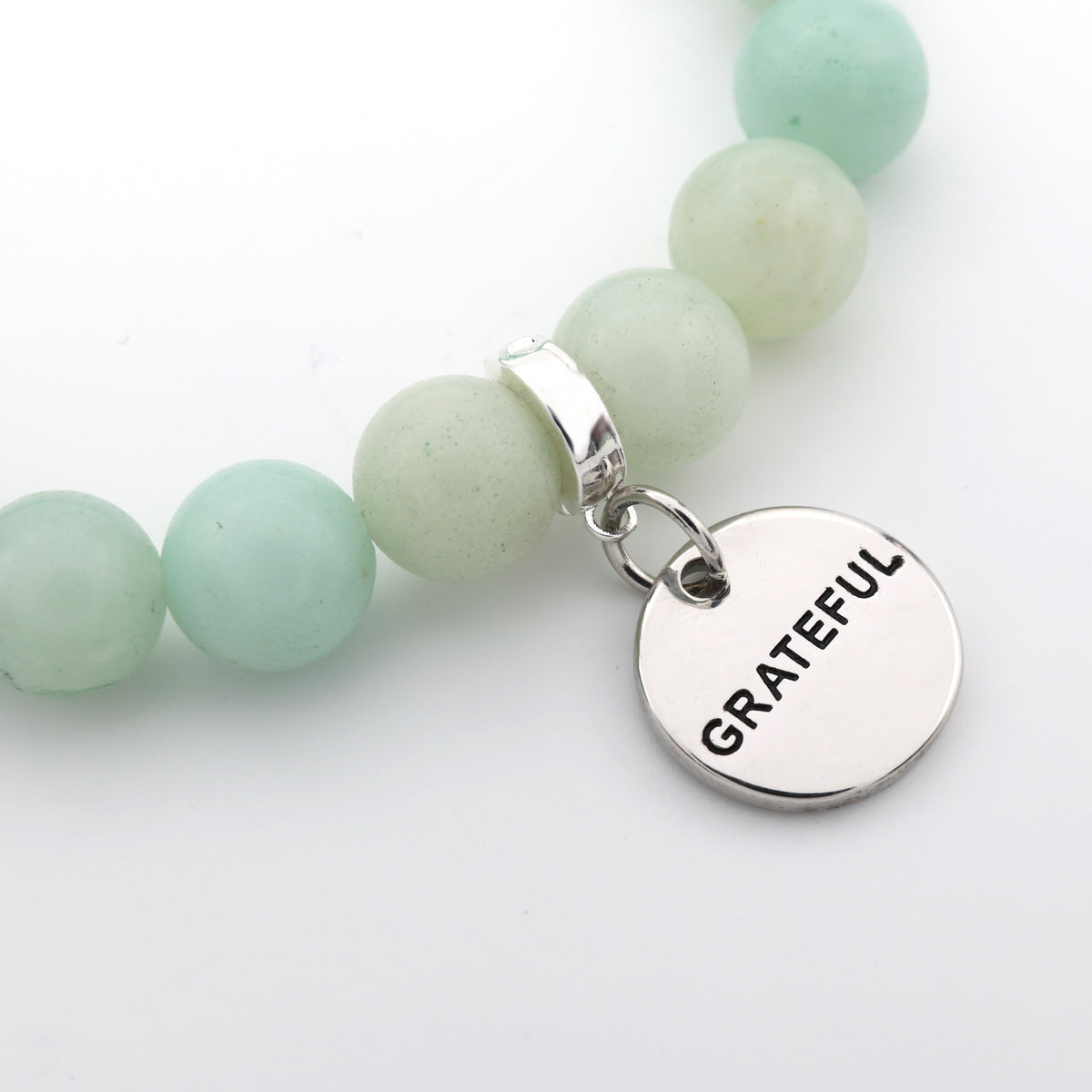 Mint green beaded bracelet with a 'GRATEFUL' charm on a white background
