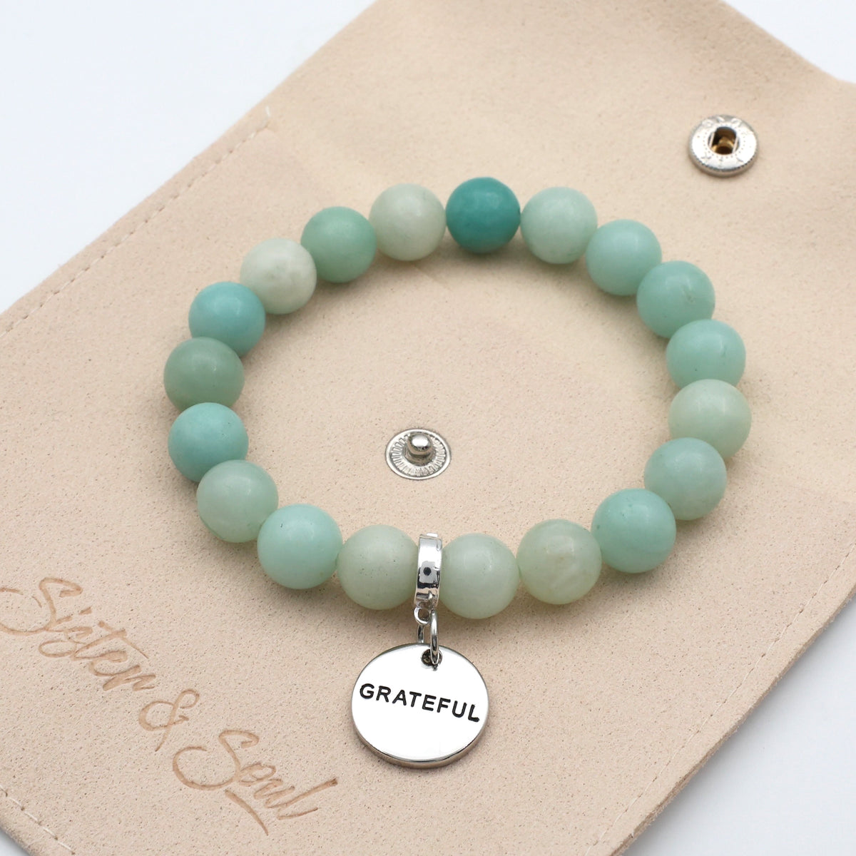 Turquoise beaded bracelet with a 'Grateful' charm on a beige card