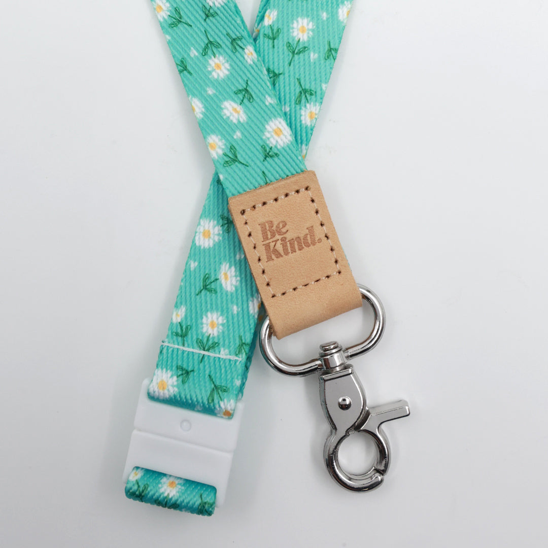 Aqua Daisies lanyard with white flowers, a tan Be Kind tab, silver-tone clasp and white breakaway fastening.