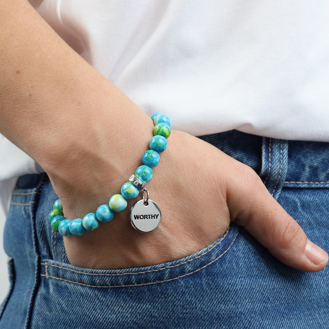 A set of three bracelets with blue and green stone beads and silver charms with the words 'strength', 'loved', and 'inspire' on them.