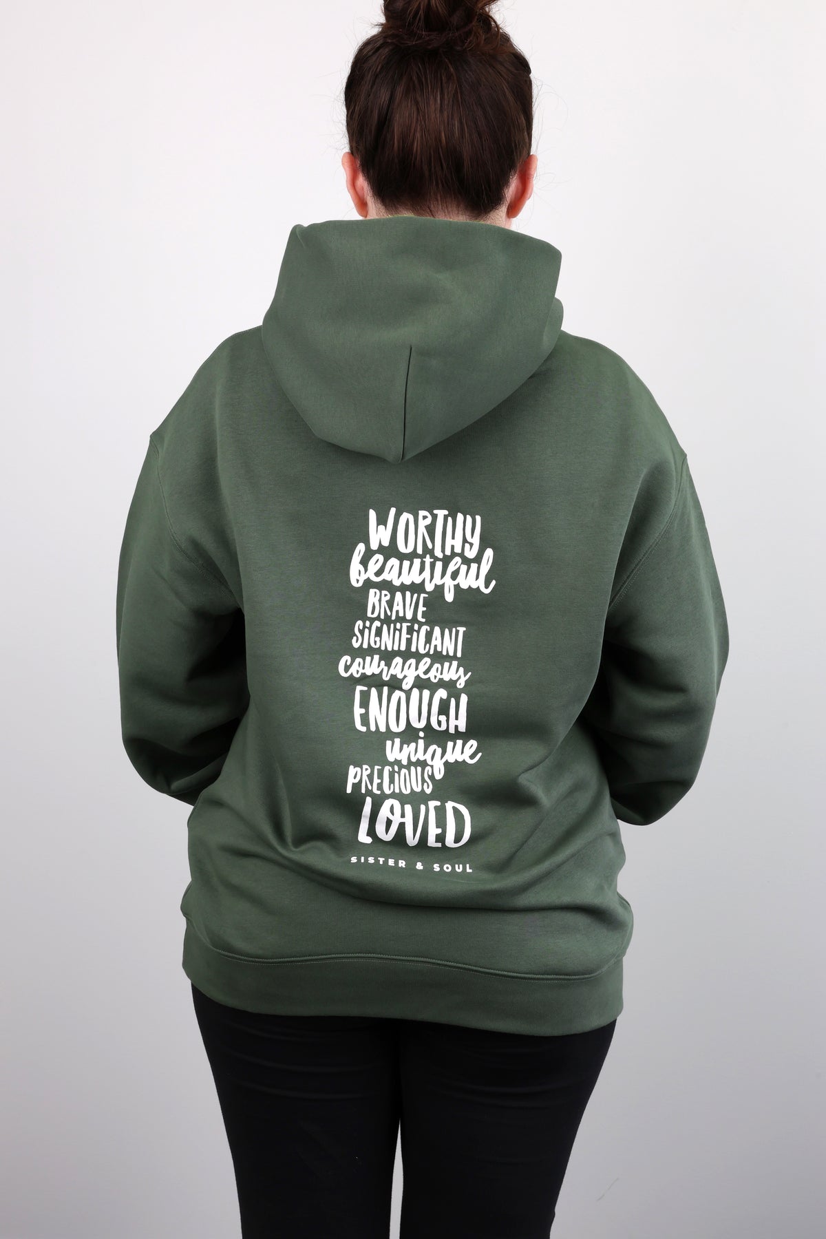 Person wearing a green hoodie with motivational text on the back against a white background