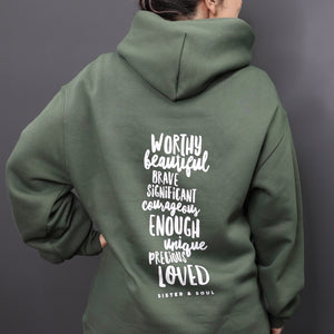 Person wearing a green hoodie with motivational text on the back against a gray background