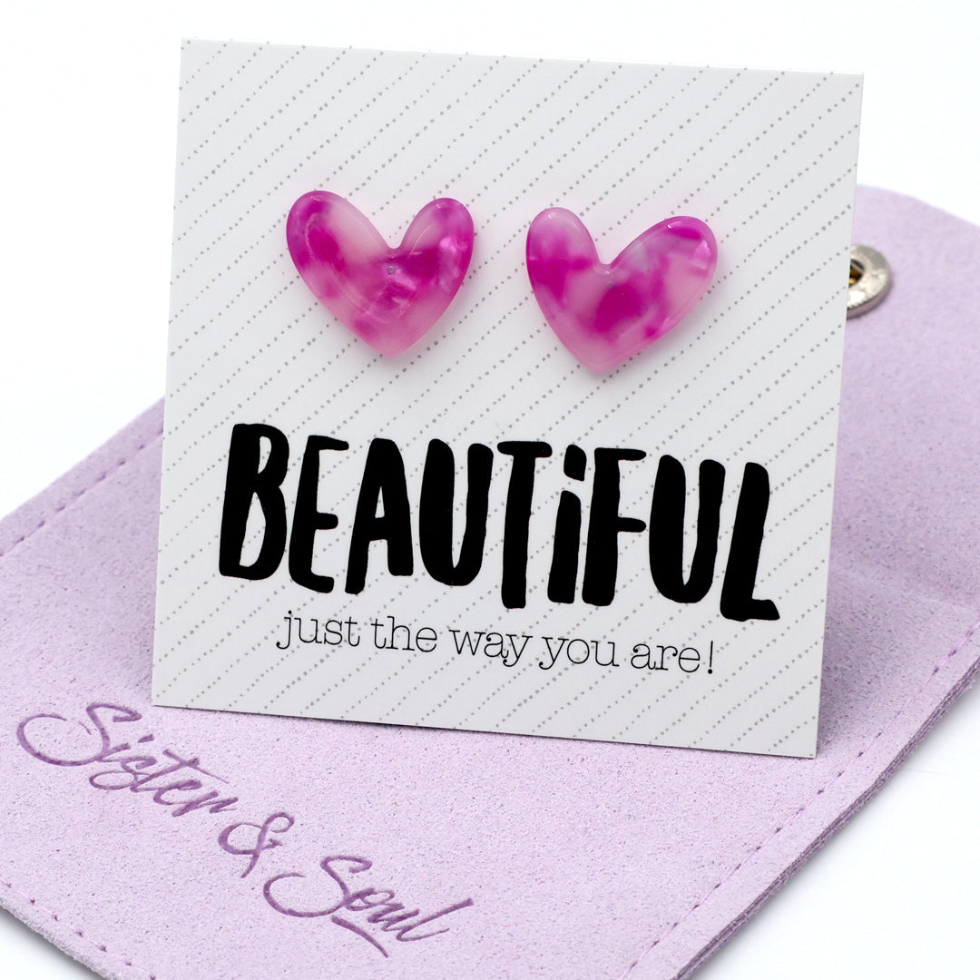 Pink marbled heart-shaped stud earrings displayed on a white card that reads 'BEAUTIFUL just the way you are!' resting on a lavender fabric pouch with ' Sister & Soul'.