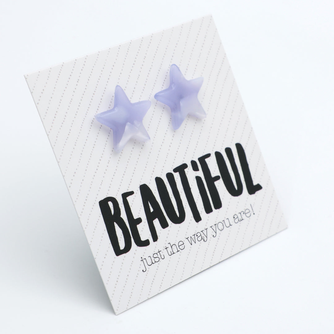 A pair of light purple star-shaped stud earrings displayed on a white square card with the text 'BEAUTIFUL just the way you are!' in black lettering.