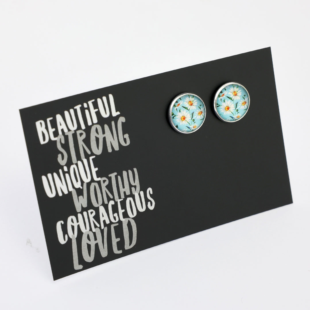 Floral earrings on a black card with motivational text