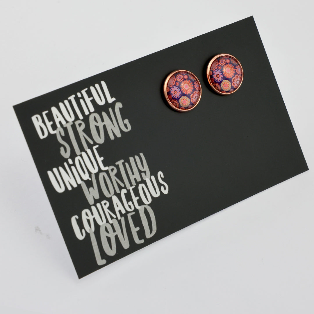 Pair of round earrings on a black card with motivational text