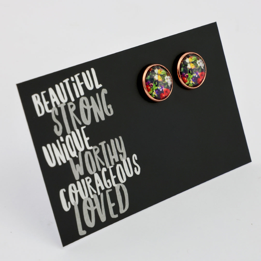 Colorful floral earrings on a black card with motivational text