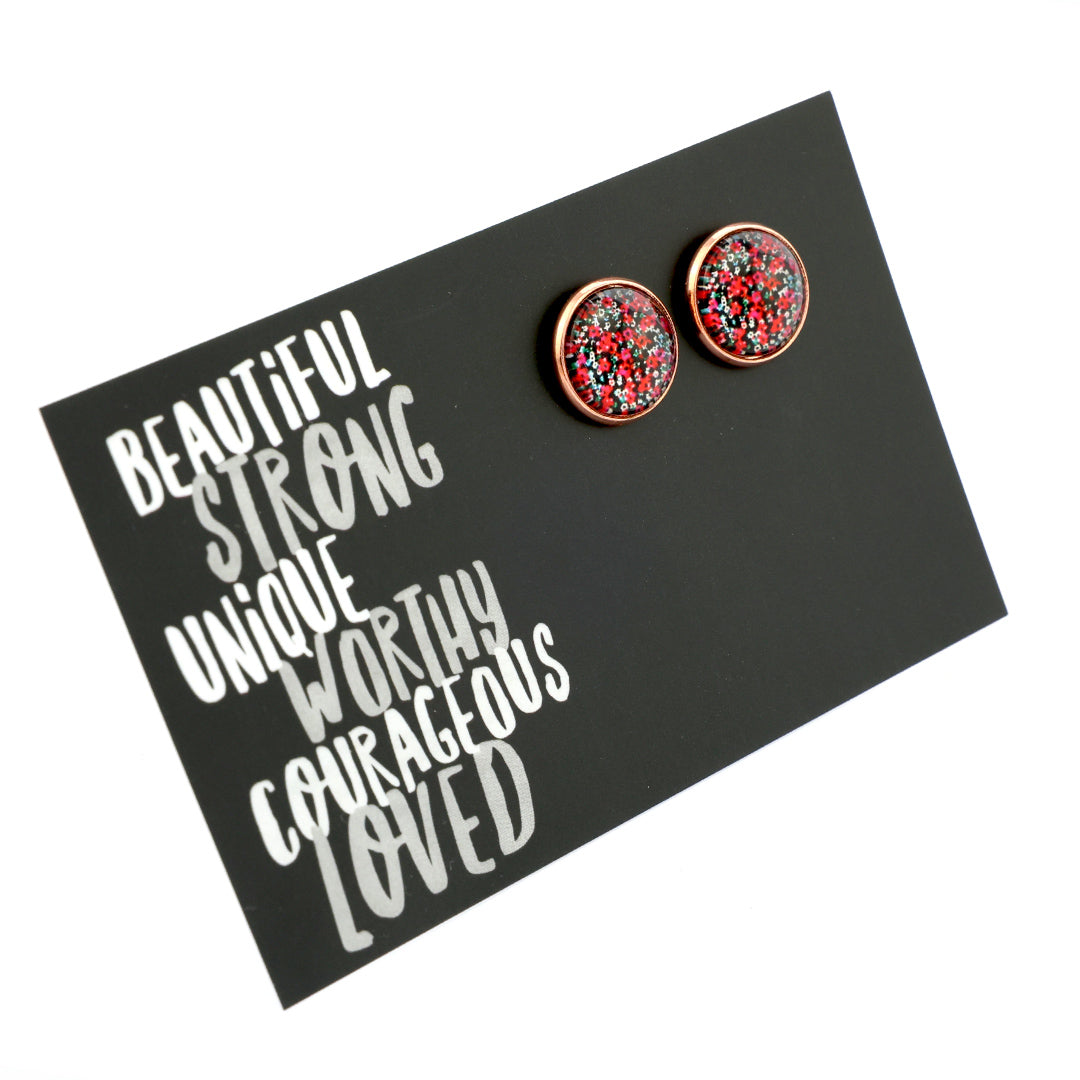 Round earrings with floral design on a black card with motivational text
