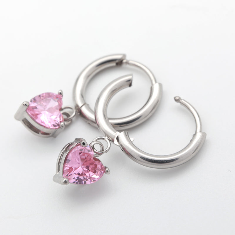 A pair of silver-toned hoop earrings with dangling heart-shaped pink gemstones, shown on a clean white background.