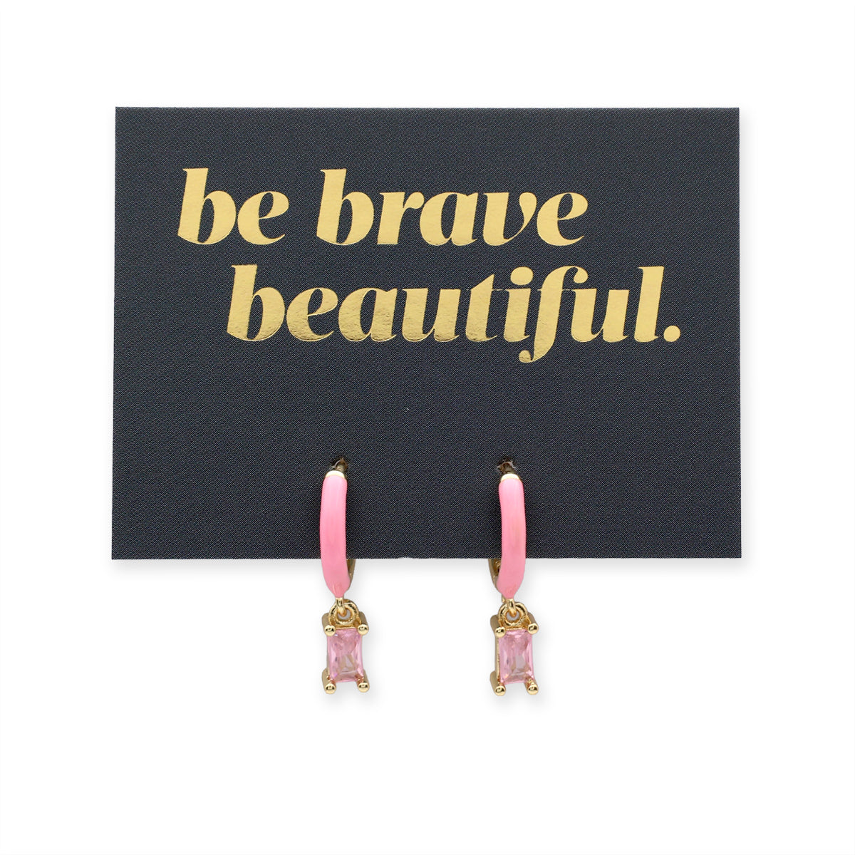 Black cards with 'be brave beautiful.' text and pink earrings on a white background
