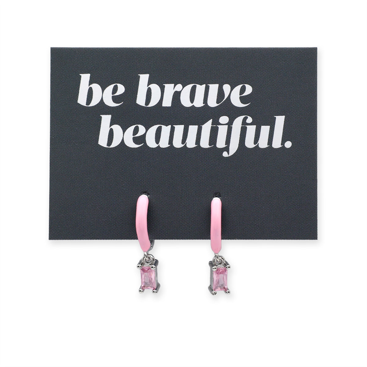 Black cards with 'be brave beautiful.' text and pink earrings on a white background