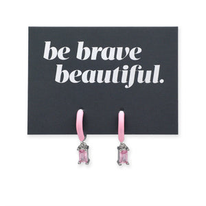 Pink earrings on a card with 'be brave beautiful' text