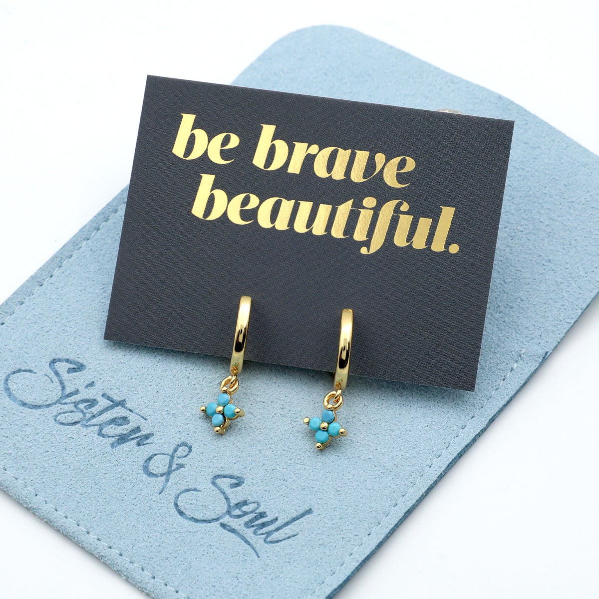 Gold earrings with turquoise stones on a 'be brave beautiful' card with 'Sister & Soul' branding.