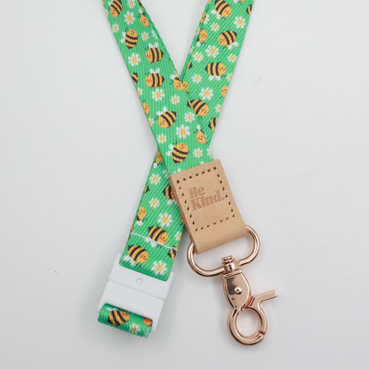 Be Kind embossed on a green bee and daisy lanyard with tan trim and a lobster clasp.