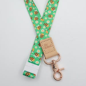 Be Kind embossed on a green bee and daisy lanyard with tan trim and a lobster clasp.