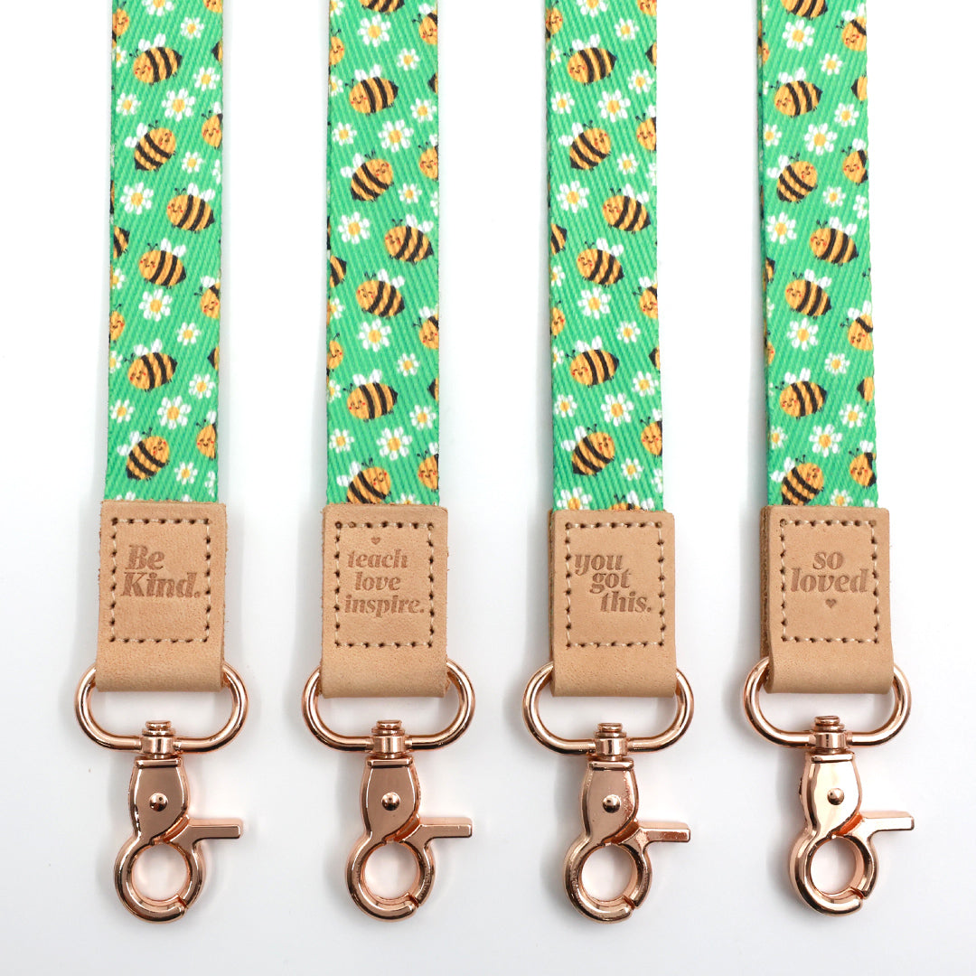 Bees lanyards showing Be Kind, Teach Love Inspire, You Got This and So Loved embossed trims and lobster clasps.
