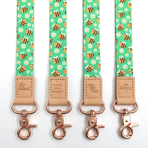 Bees lanyards showing Be Kind, Teach Love Inspire, You Got This and So Loved embossed trims and lobster clasps.