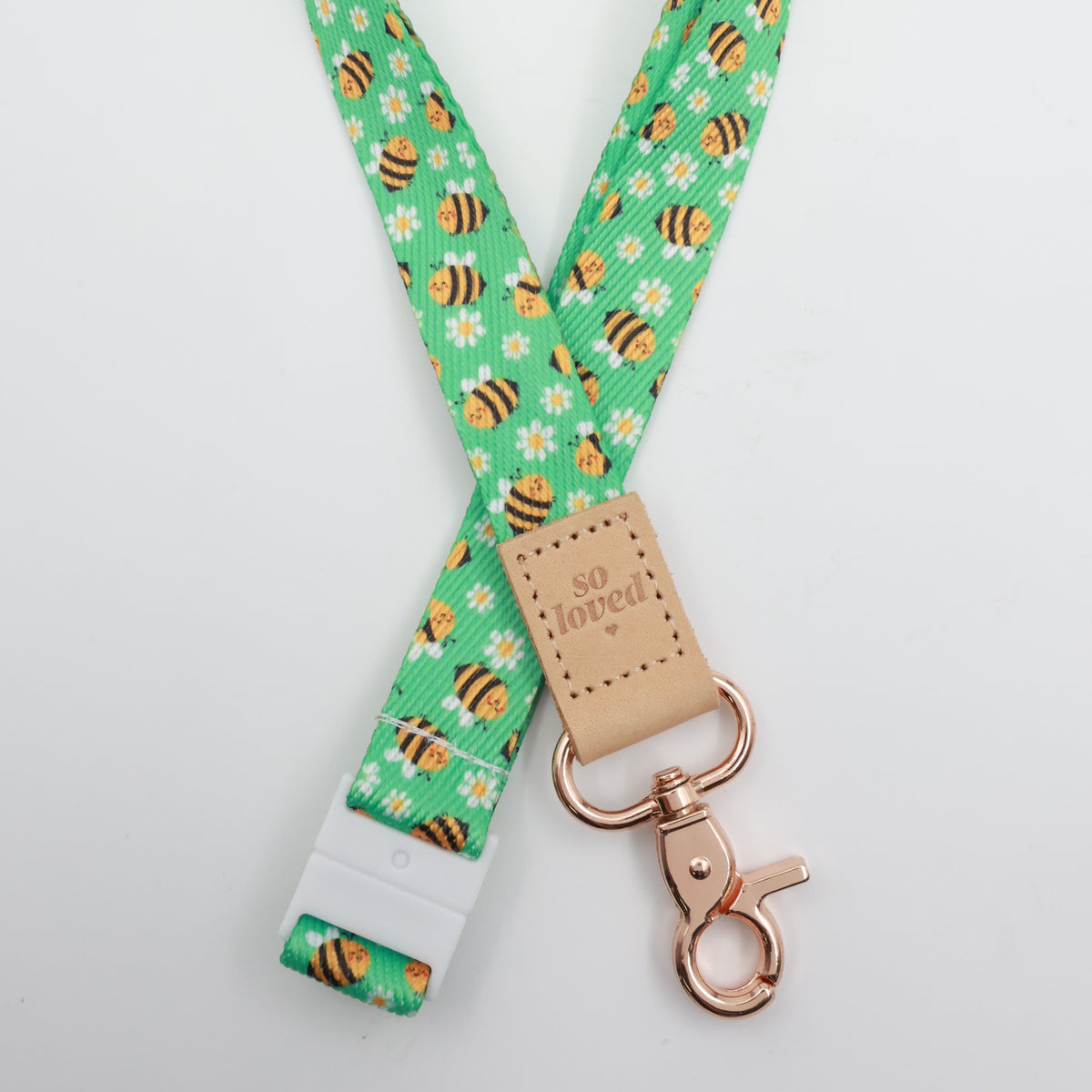 So Loved embossed on a green bee and daisy lanyard with tan trim and a lobster clasp.