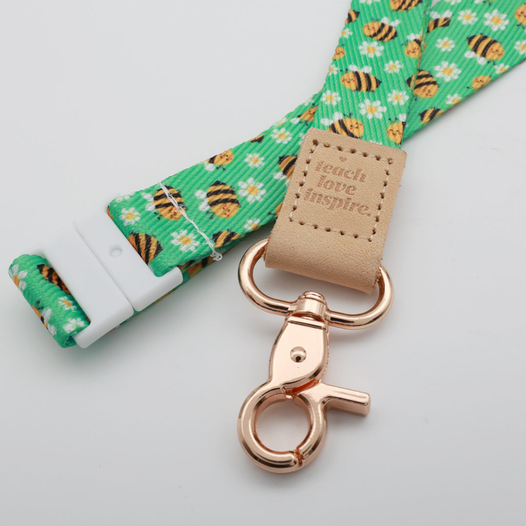 Teach Love Inspire embossed on a green bee and daisy lanyard with tan trim and a lobster clasp.