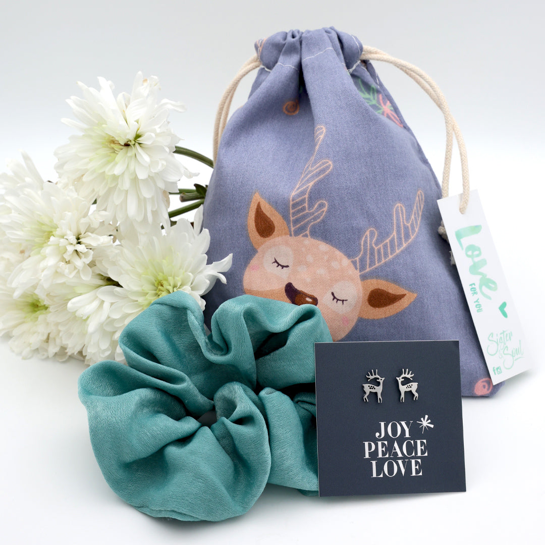 Teal scrunchie, drawstring bag with deer design, and 'Joy Peace Love' card on a white background