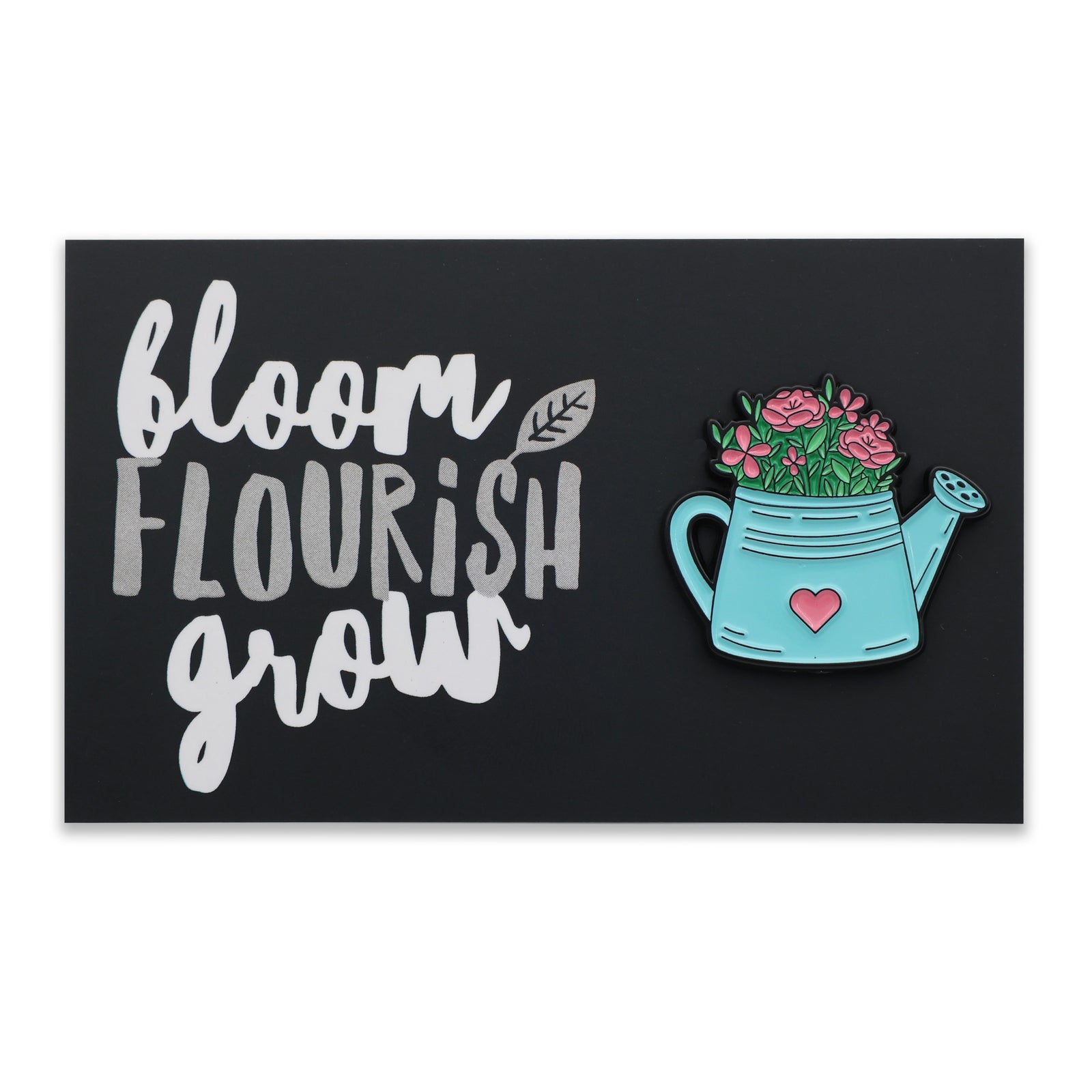 A rectangular black sign featuring the words 'bloom FLOURISH grow' in white and grey lettering, alongside a turquoise watering can with pink flowers and a small pink heart.