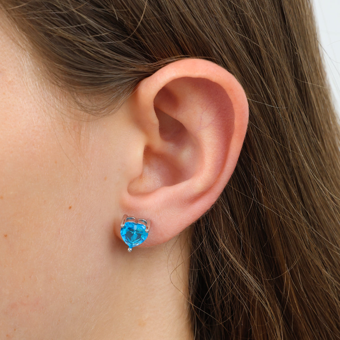 Close-up of an ear wearing a blue heart-shaped earring.