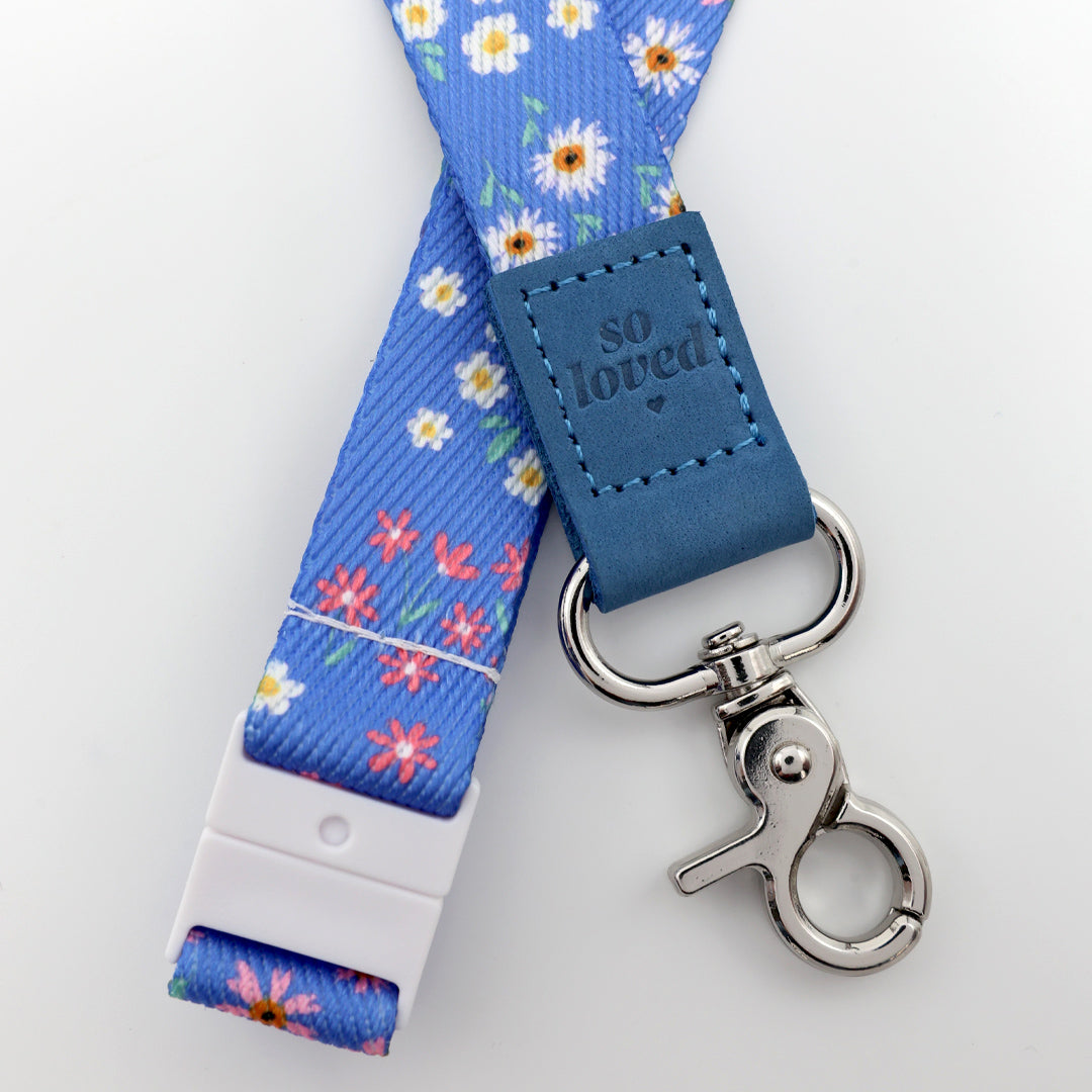 Floral lanyard with blue strap and 'so loved' tag on a white background