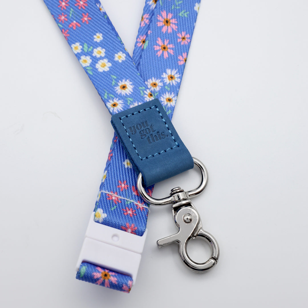 Floral lanyard with blue strap and metal clip on a light gray background