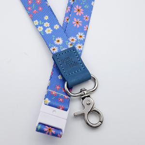 Floral lanyard with blue strap and metal clip on a light gray background