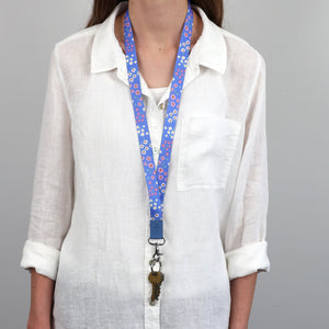 Person wearing a white shirt with a colorful lanyard and keychain against a gray background