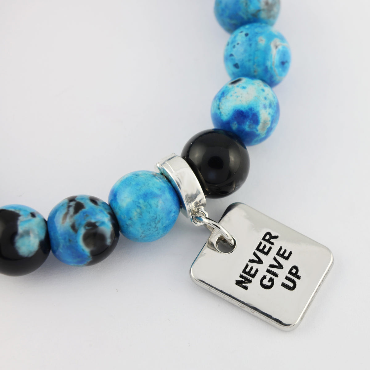 Bracelet with blue and black beads and a 'Never Give Up' charm on a white background