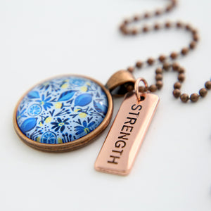 Necklace with floral pendant and 'STRENGTH' tag on a white background