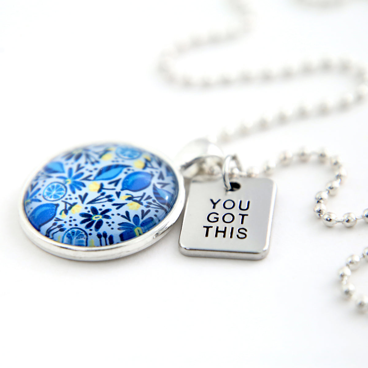Necklace with blue floral pendant and 'YOU GOT THIS' tag on a white background