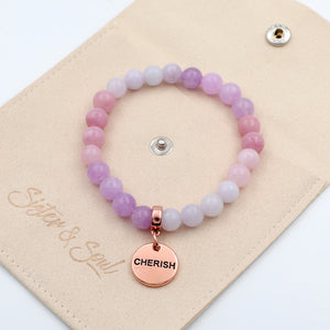 Pink beaded bracelet with 'CHERISH' charm on a beige card