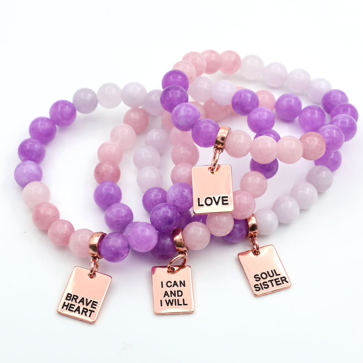 Set of beaded bracelets with motivational charms on a white background