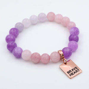 Bracelet with purple and pink beads and a 'Brave Heart' tag on a white background