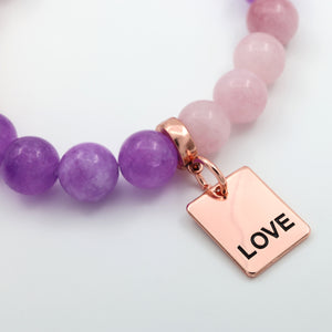 Necklace with purple and pink beads and a rose gold 'LOVE' charm on a light background