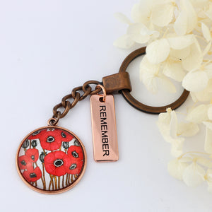 Keychain with poppy design and 'REMEMBER' tag on a white background