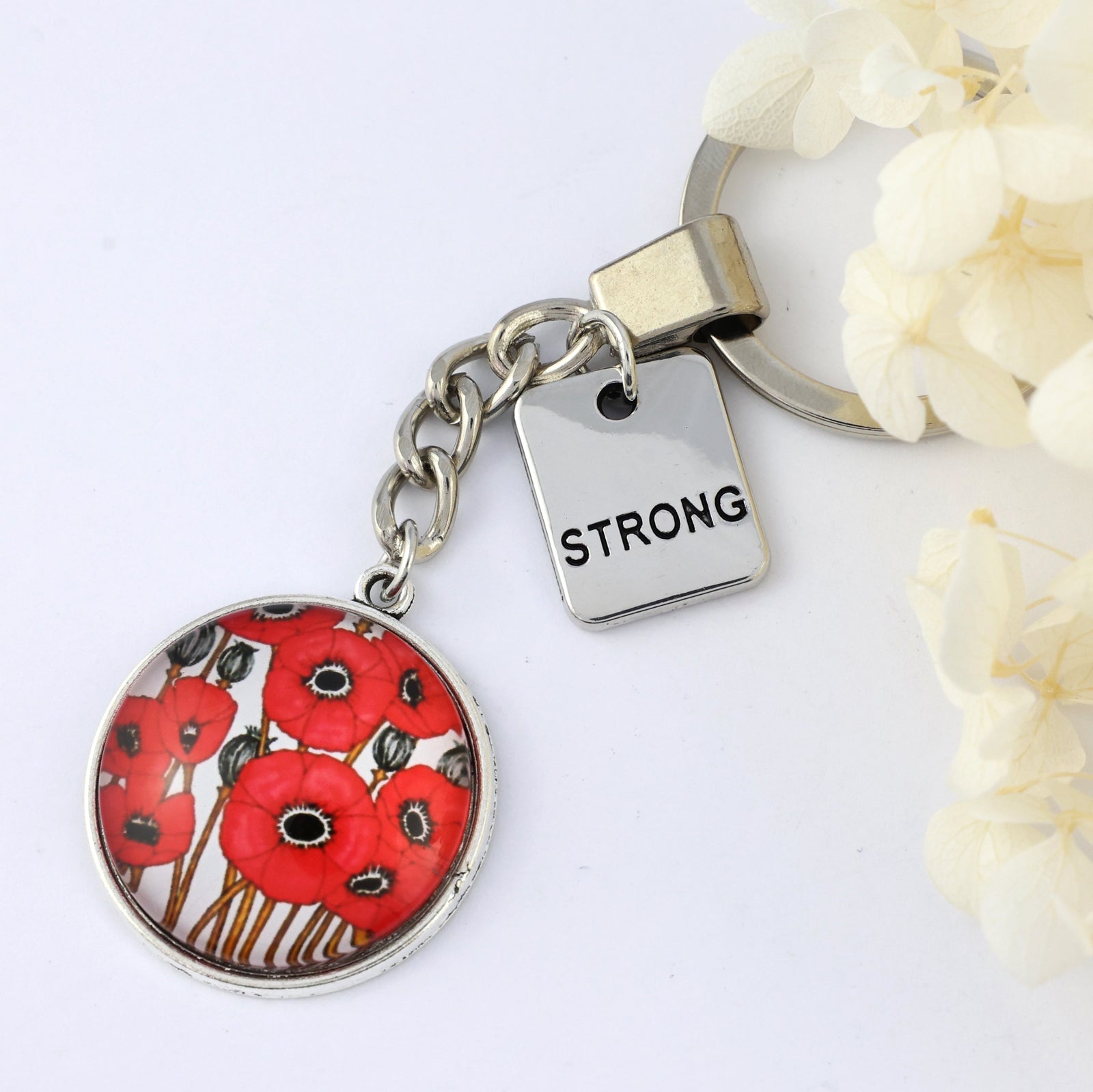 Keychain with red floral design and 'STRONG' tag on a white background