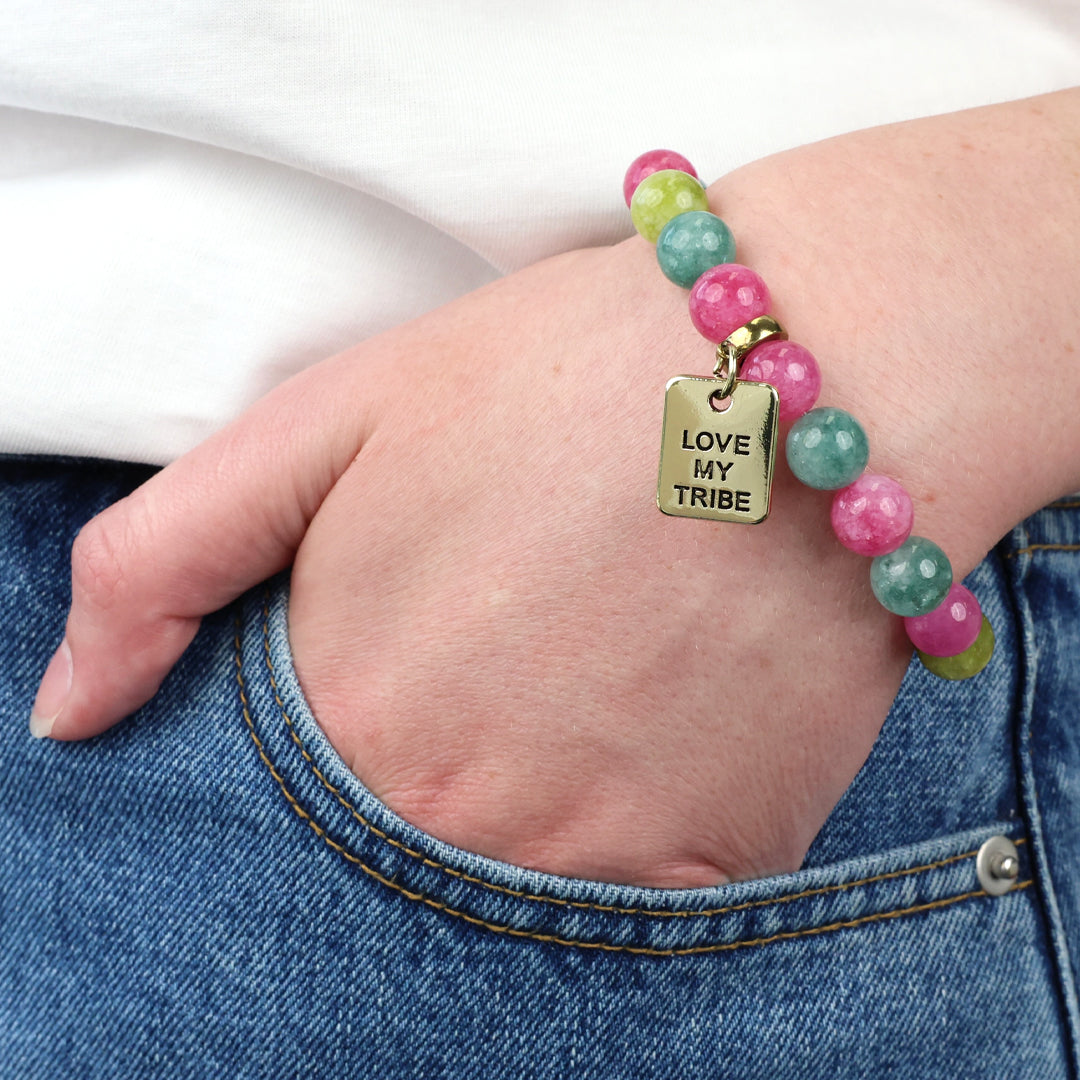 Bracelet with 'Love My Tribe' charm on a wrist, worn with jeans.